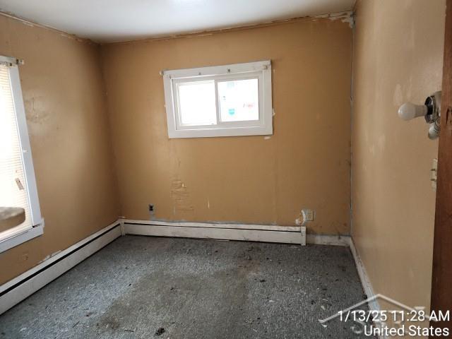 unfurnished room featuring baseboard heating