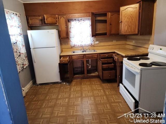 kitchen with light parquet flooring, sink, and white appliances