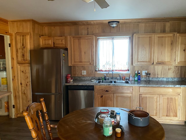 kitchen with ceiling fan, stainless steel appliances, wooden walls, and sink