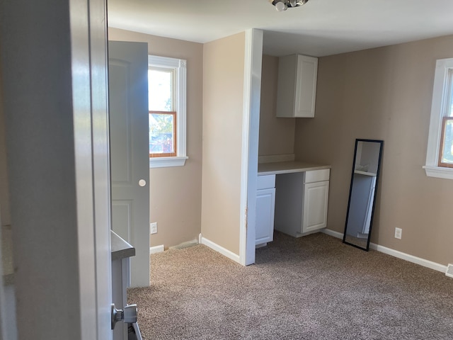 interior space with light colored carpet and built in desk