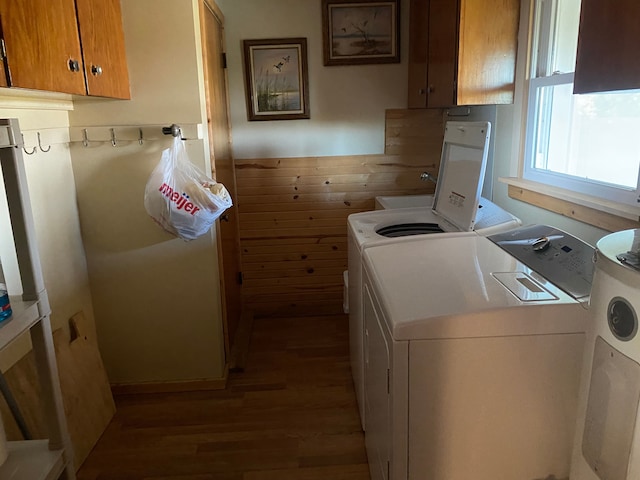 laundry room with independent washer and dryer, dark hardwood / wood-style floors, cabinets, and wood walls