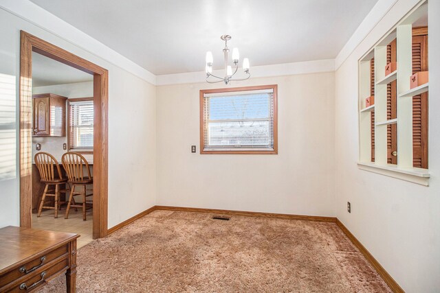 carpeted spare room featuring an inviting chandelier