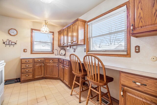 kitchen with a healthy amount of sunlight, stove, sink, and built in desk