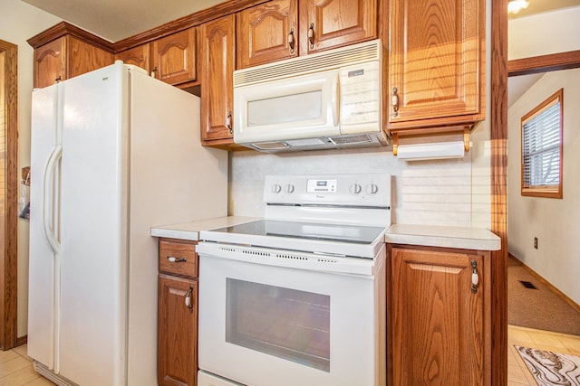 kitchen with white appliances, tasteful backsplash, light tile patterned floors, brown cabinetry, and light countertops