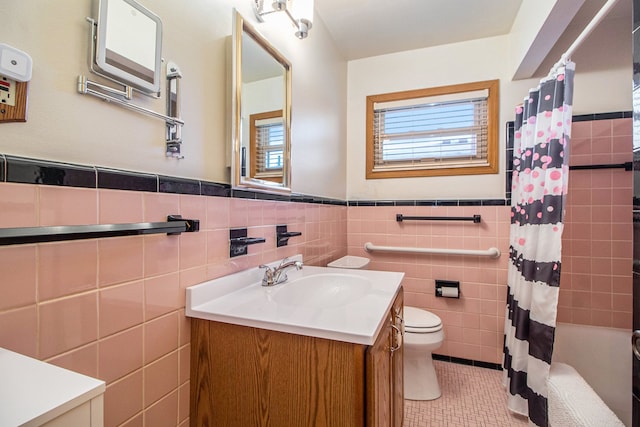 full bath featuring toilet, a wainscoted wall, vanity, tile walls, and tile patterned floors