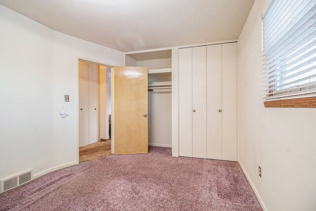 unfurnished bedroom featuring two closets and light carpet