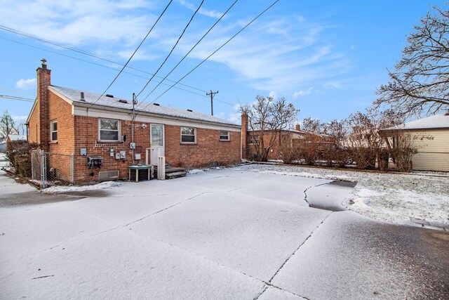 snow covered back of property with central AC