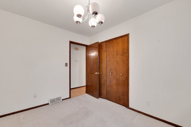 unfurnished bedroom with light colored carpet, a closet, and a chandelier