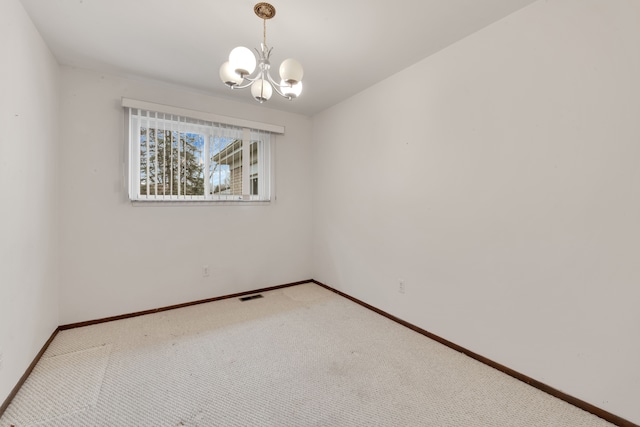 carpeted empty room with a notable chandelier