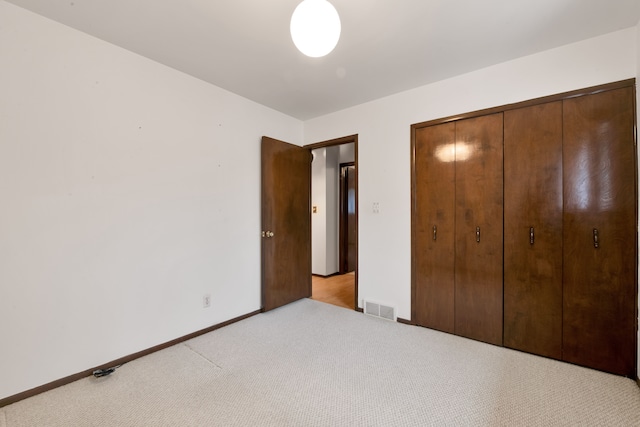 unfurnished bedroom with light colored carpet and a closet