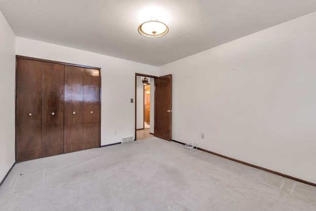 unfurnished bedroom featuring light colored carpet and a closet