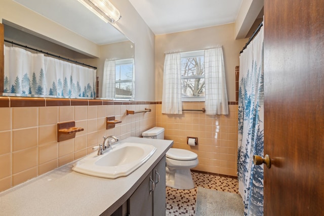 bathroom with tile patterned floors, vanity, toilet, and tile walls