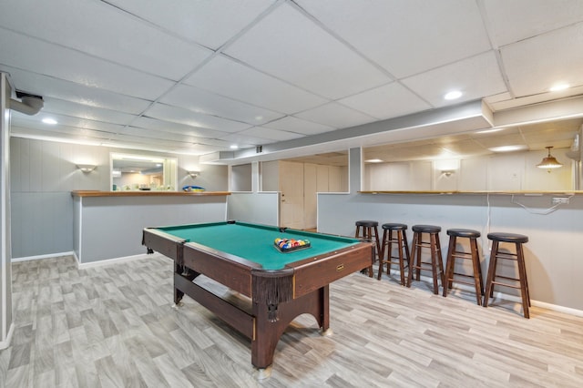 rec room featuring a paneled ceiling, bar area, pool table, and light wood-type flooring