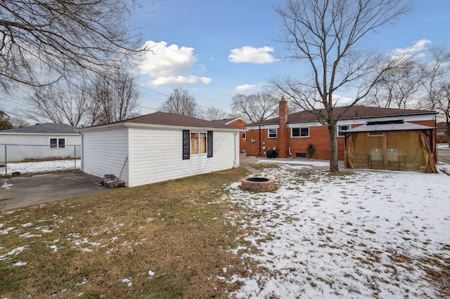 snow covered rear of property with a gazebo, an outdoor fire pit, and a lawn