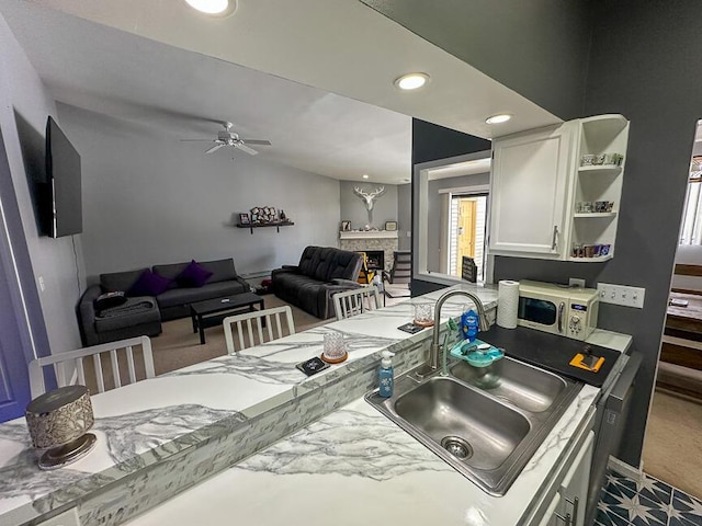 kitchen featuring white cabinetry, sink, ceiling fan, and carpet flooring