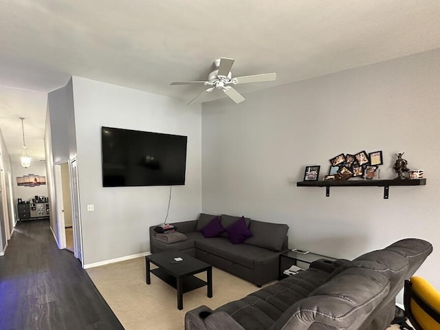 living area featuring wood finished floors, baseboards, and ceiling fan