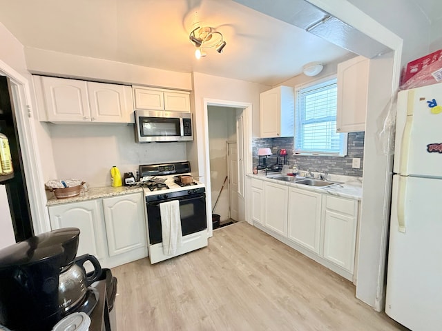 kitchen featuring white refrigerator, white cabinetry, and gas stove