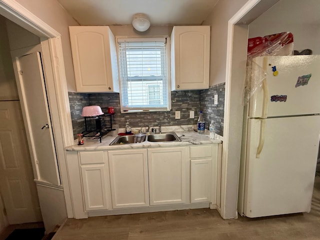 kitchen with white cabinetry, sink, light hardwood / wood-style floors, and white fridge