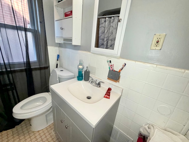 bathroom with vanity, tile walls, and toilet