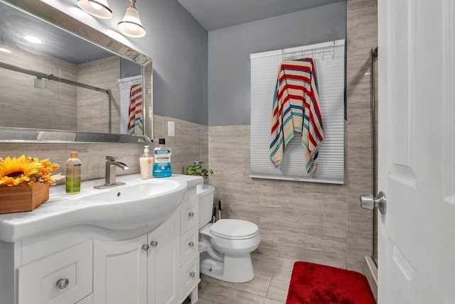 bathroom with tiled shower, vanity, toilet, and tile walls