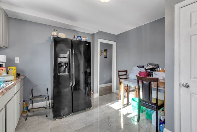 kitchen with white cabinetry and black fridge