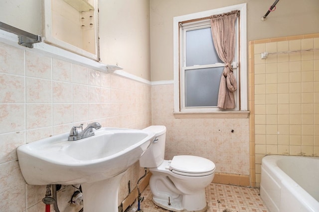 bathroom featuring tile walls, a washtub, and toilet