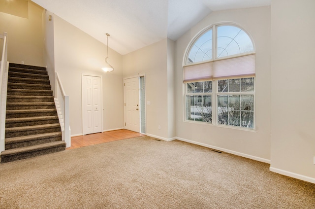 carpeted entryway featuring high vaulted ceiling