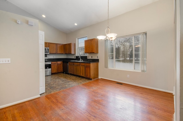 kitchen with appliances with stainless steel finishes, decorative light fixtures, sink, dark wood-type flooring, and an inviting chandelier