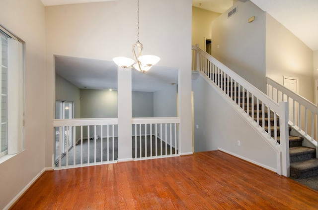 interior space with an inviting chandelier, hardwood / wood-style flooring, and a towering ceiling