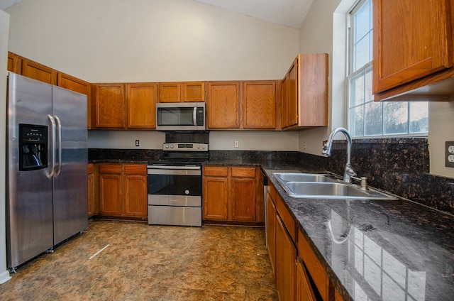 kitchen featuring sink, high vaulted ceiling, dark stone counters, and appliances with stainless steel finishes