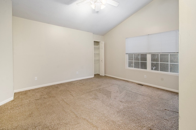 carpeted spare room featuring ceiling fan and vaulted ceiling