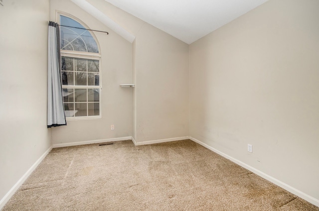 empty room featuring lofted ceiling and carpet flooring