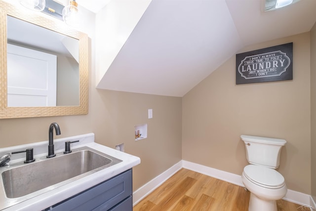 bathroom with lofted ceiling, toilet, hardwood / wood-style floors, and vanity