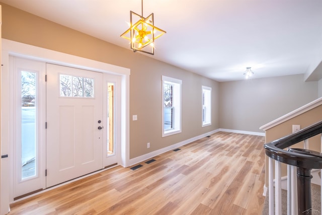 entrance foyer with an inviting chandelier, light wood-type flooring, and a wealth of natural light