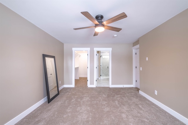 unfurnished bedroom featuring ceiling fan, a walk in closet, light carpet, and a closet