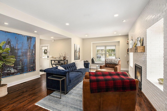 living room featuring brick wall, a brick fireplace, and dark hardwood / wood-style floors