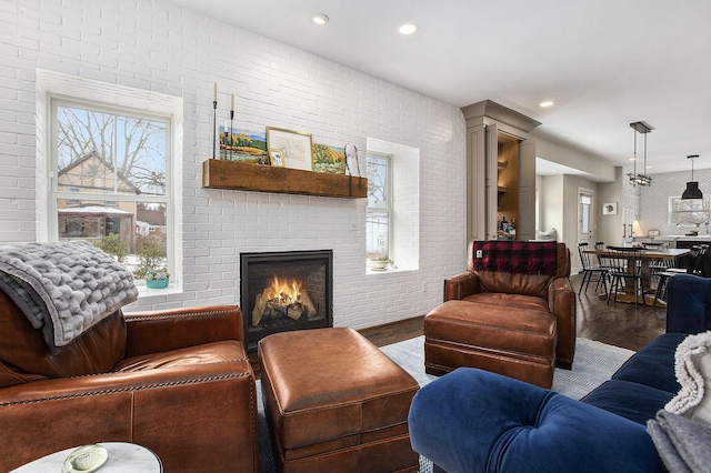 living room featuring brick wall, a fireplace, and dark hardwood / wood-style flooring