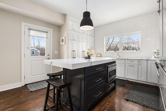 kitchen with white cabinetry, dark wood-type flooring, pendant lighting, and backsplash