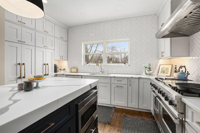 kitchen with wall chimney exhaust hood, stainless steel appliances, sink, and backsplash