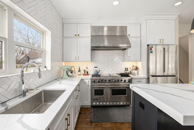 kitchen featuring sink, appliances with stainless steel finishes, backsplash, light stone counters, and wall chimney exhaust hood