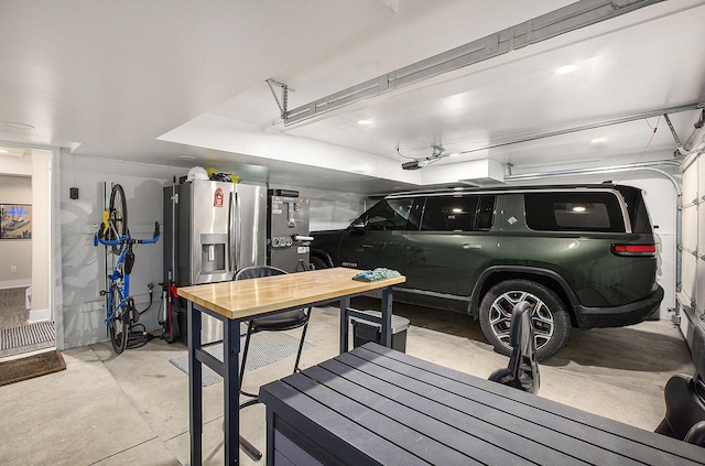 garage with a garage door opener and stainless steel fridge with ice dispenser