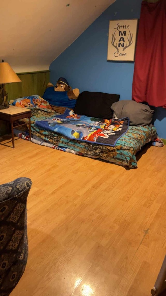 bedroom with wood-type flooring and vaulted ceiling