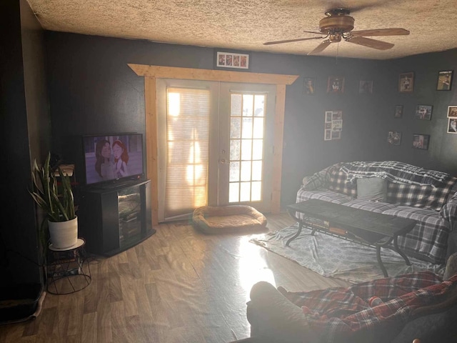 bedroom with ceiling fan, hardwood / wood-style floors, a textured ceiling, and french doors