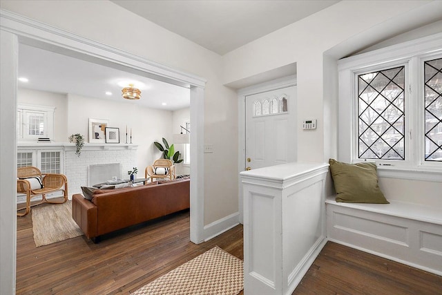 interior space with dark wood-type flooring and a brick fireplace