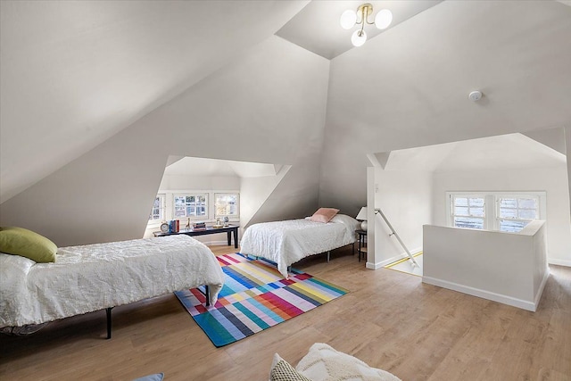 bedroom featuring multiple windows, high vaulted ceiling, and light wood-type flooring