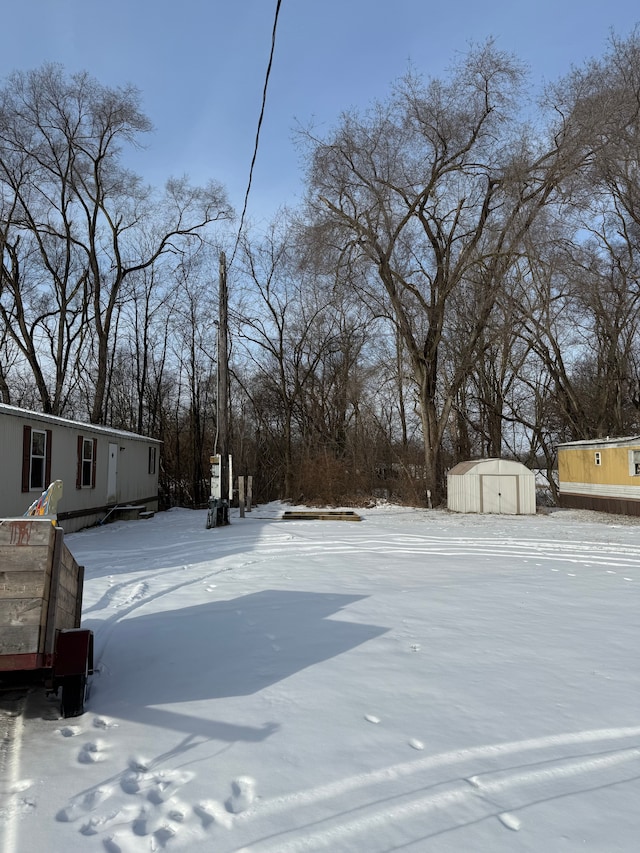 yard covered in snow featuring a storage shed