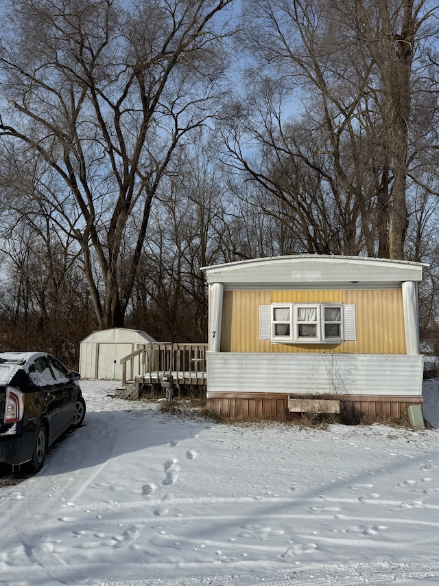 snow covered property with a storage shed