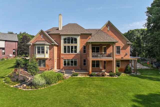 rear view of house with a balcony, a yard, and a patio area