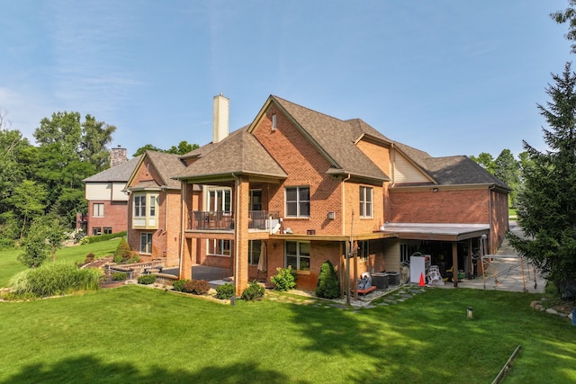 rear view of property with a balcony, a yard, central AC unit, and a patio area