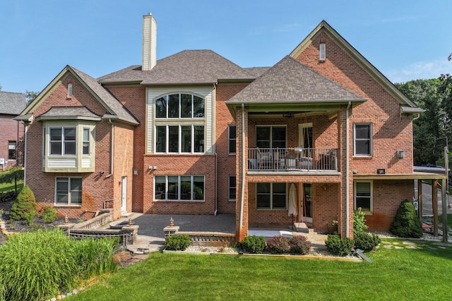 rear view of house featuring a patio, a balcony, and a lawn